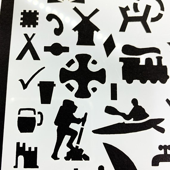 Adventures Journal Stencil, Travel A5 Journal Sized Stencil with adventure activity shapes & OS Symbols, craft mylar stencil - a close up of the left side showing some OS symbols, a windmill, phone, tent, canoe, hiker, train, beer, castle