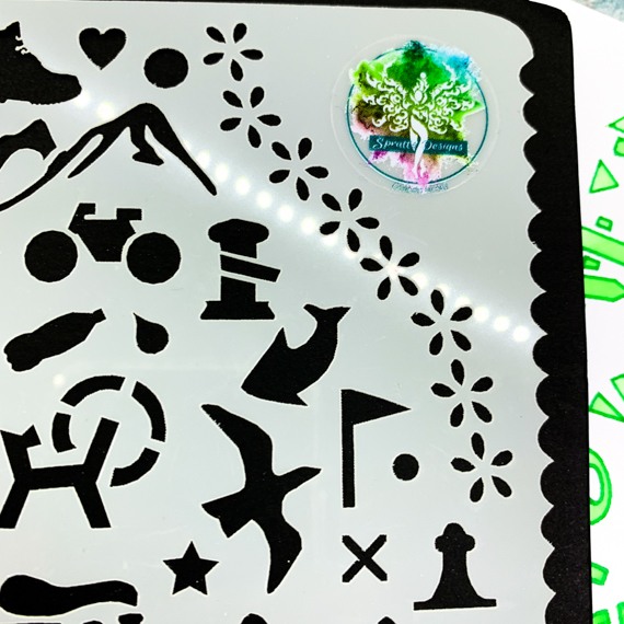 Adventures Journal Stencil, Travel A5 Journal Sized Stencil with adventure activity shapes & OS Symbols, craft mylar stencil - A close up of the top right corner showing shapes from the OS map, mountains, a floral swag, boot, bottle, flag, bird, bicycle