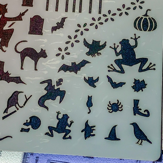Magical Creatures Journal Stencil, Mythical wizardry Craft Stencil, Dragons, Fairies, witches, Pegasus, bats, cats, fairy, mermaids. A close up of the bottom right corner showing, cat, gravestone, grave side railings, bat, owl, frog, ghost, witches head, witches hat, spider, cat, leaf, boot, crow, raven, pumpkin.