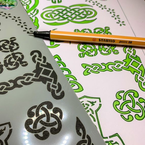 Celtic Journal Stencil Design 2 close up of right side, to the right is a journal page showing the stencil used with green inks and a pen laying across the page