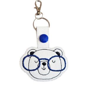 Bear Face with Glasses Keyring featuring an embroidered bear face wearing blue glasses on white faux leather, with silver clasp and snap button.