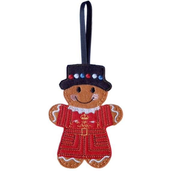 Beefeater Gingerbread Character made from felt, wearing a red and gold uniform and a black hat with colourful dots, shown as a hanging decoration with a black ribbon loop.