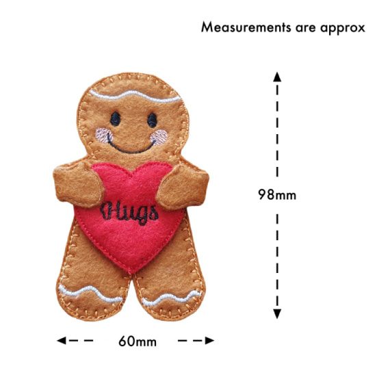 Handmade felt gingerbread character holding a red heart embroidered with the word 'Hugs.' The gingerbread has stitched icing details, a smiling face, and pink cheeks. Approximate measurements are shown: 98mm tall and 60mm wide.