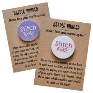 Two round magnetic needle minders shown on kraft card packaging. One has a purple background with white text reading ‘Stitch PLEASE!’, the other has a white background with pink text.