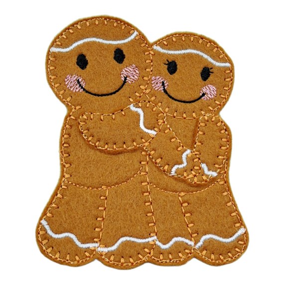 Handmade gingerbread sweethearts – couple in love, with smiling embroidered faces and pink cheeks.