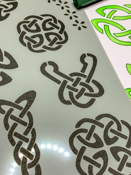 Celtic Knots Design 3 Journal Stencil - A close up of the Left hand side of the stencil with a page peeking out beneath showing the stencil having been used with green inks.