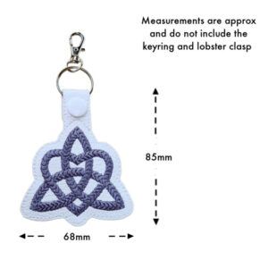 White faux leather Trinity Heart Celtic Knot keyring with grey embroidery, white snap button, and metal clasp. The image includes measurements showing 85mm in height and 68mm in width, with a note stating measurements do not include the keyring or lobster clasp.