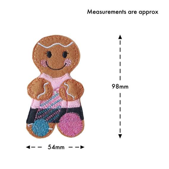 A smiling felt crochet gingerbread character with cosy stitched details, a pink top, patterned skirt, and balls of yarn, shown with approximate measurements of 98 mm tall and 54 mm wide.