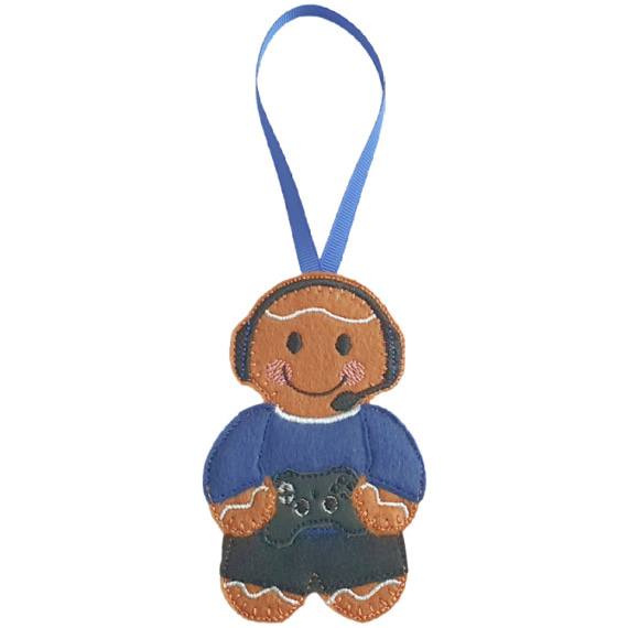 A felt gamer gingerbread decoration with a blue hanging ribbon, wearing a blue top and black trousers, smiling while holding a small black game controller.