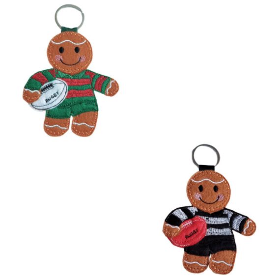 Two felt gingerbread rugby player keyrings, one wearing a green and red striped kit holding a white rugby ball stitched with “Rugby,” and the other wearing a black and white striped kit holding a red rugby ball.