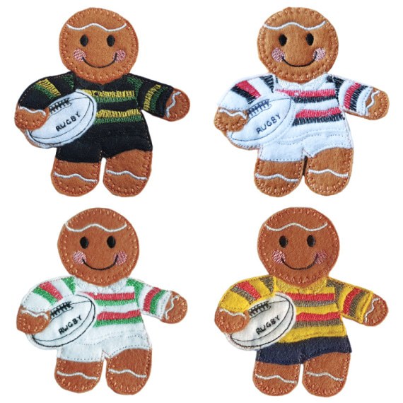 Four felt gingerbread rugby player characters, each wearing different coloured striped kits and holding a white rugby ball stitched with the word “Rugby.” The kits include black and yellow, white with red and blue, white with green and red, and yellow with red and navy stripes.