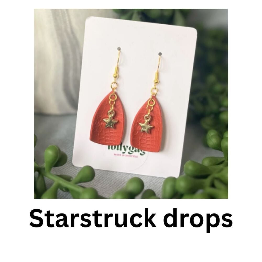 Red faux leather look polymer clay drop earrings with gold star charms, handmade in Sheffield and displayed on a Lollygag jewellery card.