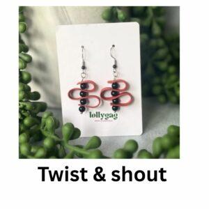 Handmade red polymer clay earrings with twisted loop design and black bead accents, textured to resemble faux leather, displayed on a Lollygag card.