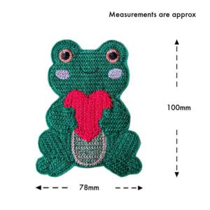 Smiling felt frog holding a heart, machine embroidered with a knit stitch pattern, shown on a white background with approximate measurements of 78mm wide and 100mm tall.