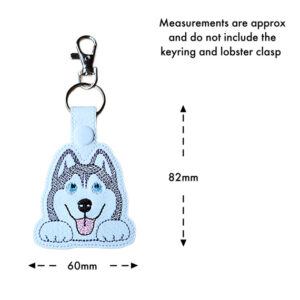 Kawaii Husky keyring with embroidered husky face and blue eyes, shown with measurements of 82mm in height and 60mm in width. The image notes that measurements do not include the keyring and lobster clasp.