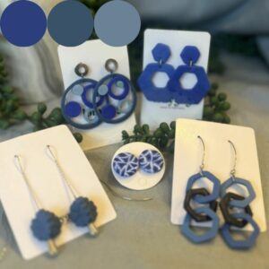 Group of handmade blue polymer clay earrings from the Azure Collection by Lollygag Jewellery, featuring geometric and sculptural designs in ocean-inspired tones, displayed on white cards.