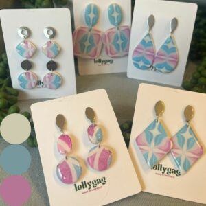 Overview of the Collection Step into vintage artistry with the Transcendent Swirls Collection from Lollygag Jewellery — where heritage design meets modern colour expression. Each piece in this collection is handcrafted in Sheffield from authentic 1970s wallpaper, carefully preserved within polymer clay to showcase its pastel swirls and retro textures. What was once interior décor now becomes wearable art — joyful, nostalgic, and truly one of a kind. Inspired by the dopamine dressing trend, this feel-good collection celebrates creative reuse, sustainability, and individuality. The soft tones of pink, blue, and ivory evoke calm, optimism, and artistic freedom, while the swirling marbled designs capture the effortless movement of mid-century printmaking. Though partly inspired by the palette of the Transgender Pride Flag, the heart of the collection lies in transforming reclaimed materials into contemporary expressions of joy and creativity. Each pair is lightweight, hypoallergenic, and designed for comfort, movement, and timeless character — connecting the past and present through colour, craftsmanship, and joyful self-expression. Collection Highlights Handmade in Sheffield, UK Crafted from genuine 1970s wallpaper Inspired by dopamine dressing and vintage design Lightweight polymer clay, sealed for durability Nickel-free, hypoallergenic findings Gift-ready eco packaging Ships within 1 working day The Collection Includes Transcendent Cascade – £20.00 Flowing, fluid, and full of retro charm — a triple-drop design showcasing original wallpaper swirls. Gentle movement and silver-toned accents create a sense of freedom and flow, perfect for everyday wear with a hint of 70s glamour. Transcendent Diamond – £20.00 Elegant geometry meets vintage texture. Bold diamond silhouettes highlight soft pink and powder blue marbling, sealed beneath a smooth clay finish. A striking balance of retro detail and modern minimalism. Transcendent Mosaic – £20.00 Circular shapes and marbled patterns unite in this design celebrating artistic balance and handcrafted charm. Playful yet poised, perfect for colour lovers and vintage enthusiasts alike. Transcendent Teardrop – £20.00 Graceful and timeless, this softly curved design highlights the wallpaper’s natural marbling within a fluid silhouette. Lightweight, nostalgic, and effortlessly wearable. Transcendent Tiles – £20.00 – SOLD OUT Graphic and nostalgic, this design reimagines vintage interior patterns as bold, contemporary statement jewellery — transforming retro texture into modern wearable art. Collection Summary The Transcendent Swirls Collection is a joyful tribute to colour, creativity, and reclaimed beauty. Each pair is handmade in Sheffield from genuine vintage wallpaper, reimagined through the lens of dopamine dressing. Feel-good jewellery that connects eras, celebrates individuality, and turns retro texture into modern self-expression.
