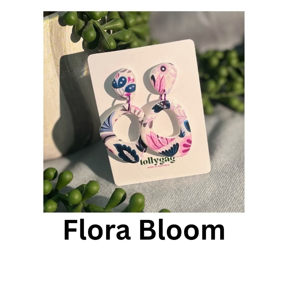 Flora Bloom earrings featuring soft oval polymer clay drop shapes decorated with bold pink and cobalt blue 1970s floral wallpaper, handmade in Sheffield.