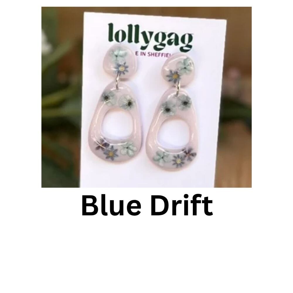 Blue Drift earrings by Lollygag Jewellery, featuring pressed blue wildflowers set into soft pink polymer clay and sealed with clear resin, creating lightweight botanical drop earrings handmade in Sheffield.