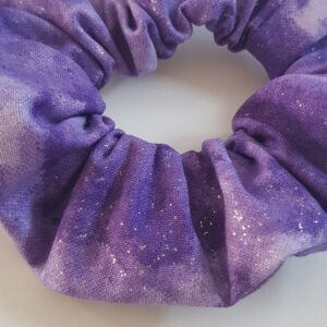 Handmade purple glitter cotton scrunchie on a white background.
