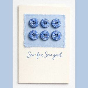 Handmade sewing pun button card with six blue patterned polymer clay buttons sewn onto pale blue fabric, featuring the phrase Sew far, sew good on a cream greeting card.