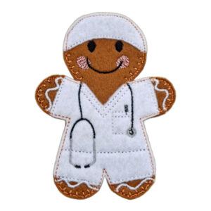 A handmade felt anaesthetist gingerbread character featuring embroidered black eyes, a smiling mouth, pink cheeks, and decorative icing-style stitching. The character wears white scrub trousers and tunic with an embroidered stethoscope and matching scrub cap. Displayed on a clean white background.