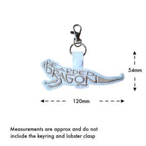 Embroidered bearded dragon word art keyring on white faux leather with grey stitching, measuring approximately 120mm wide and 54mm high, excluding the keyring and lobster clasp.