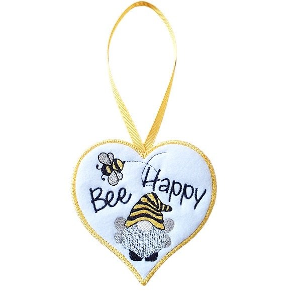 White felt heart-shaped hanging decoration with the words “Bee Happy” embroidered in black, featuring a small bee and an embroidered gnome wearing a yellow and black striped hat. The heart has a yellow stitched border and hangs from a matching yellow ribbon loop against a white background.