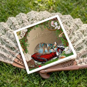Cheshire cat card lying on top of a fan on grass