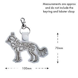 Chinese Crested word art keyring in a standing dog silhouette, embroidered on faux leather with the words “Chinese Crested” forming the body of the design. Measurement guide shows the design approximately 100mm wide and 70mm tall, not including the keyring and lobster clasp.