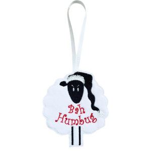 Handmade felt sheep Christmas decoration with a black face and legs, wearing a Santa hat and embroidered with “Bah Humbug” in red text, hanging from a white ribbon loop.