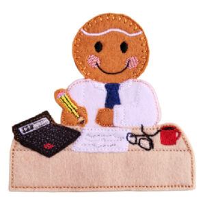 Felt gingerbread accountant character seated at a small desk with papers, glasses, a calculator, a pencil, and a hot mug, with neat embroidered details and a smiling face.
