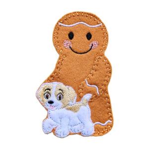 A handmade felt gingerbread character with a smiling face and pink cheeks, holding a small white and tan dog with embroidered details.