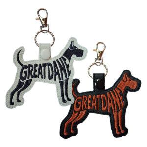 Embroidered Great Dane word art keyrings on white and black faux leather, with the dog silhouette forming the words 'Great Dane', attached to a metal split ring and lobster clasp.