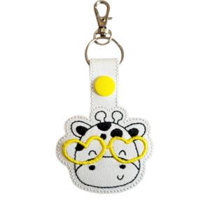Happy Giraffe with Glasses Keyring featuring an embroidered giraffe face wearing yellow heart-shaped glasses on white faux leather, with a yellow snap button and silver clasp.
