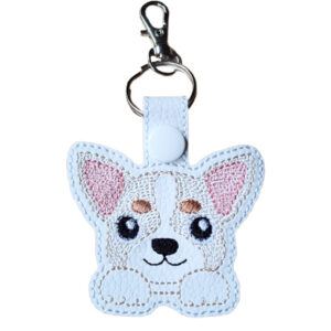 A kawaii-style Chihuahua keyring made from white faux leather, featuring an embroidered design of a cute Chihuahua face with large pink ears, brown patches, and a small smiling mouth. The keyring includes a white snap fastener, silver keyring, and lobster clasp.