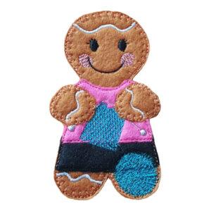 A smiling felt gingerbread character dressed for knitting, with stitched details, a cosy pink top, a patterned skirt, and a ball of yarn by their side.