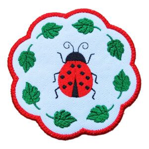 A small round decorative candle coaster with a scalloped red border, featuring an embroidered red ladybird surrounded by green leaves on a white background.