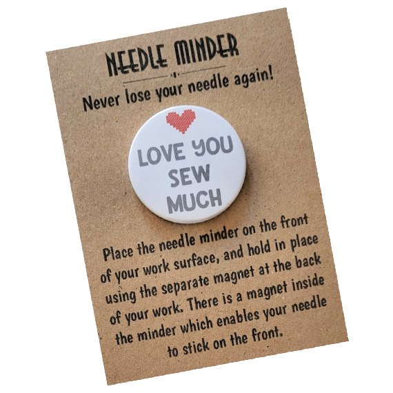 Round magnetic needle minder, white background with grey lettering that says ‘Love You Sew Much,’ and a stitched-style red heart in the centre. Presented on kraft card.