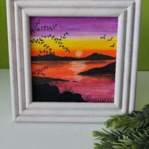 Marble effect square frame with pink, orange, yellow and purple sunset over water