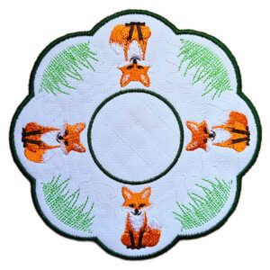 Embroidered woodland fox tealight cover with repeating fox design, green grass details, and circular centre opening, finished with a dark green scalloped edge