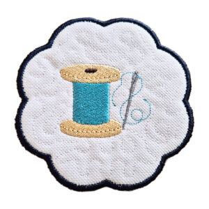 Embroidered needle and thread candle coaster with scalloped edge, featuring a spool of thread and stitched detail on a white background.