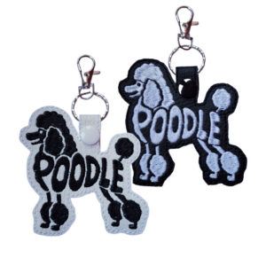 Two Poodle word art keyrings in a standing dog silhouette, embroidered on faux leather with the word “Poodle” forming the body of the design. One keyring is shown in white faux leather with black stitching and the other in black faux leather with white stitching, both attached to metal split rings with lobster clasps.