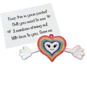 Embroidered rainbow heart pocket hug charm with a smiling face and outstretched arms, made from soft felt. Displayed with a keepsake poem card that reads: ‘Keep this in your pocket until you need to see a rainbow shining out, with love to you, from me.