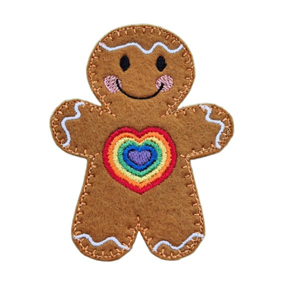 Handmade felt gingerbread character with stitched icing details and a smiling face, featuring a rainbow heart design on the chest.
