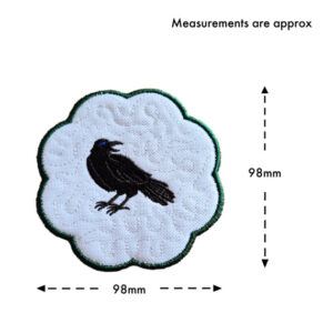 Embroidered raven candle coaster with scalloped edge, shown with approximate measurements of 98mm by 98mm, featuring a black raven on a textured white background with a subtle stippled pattern.