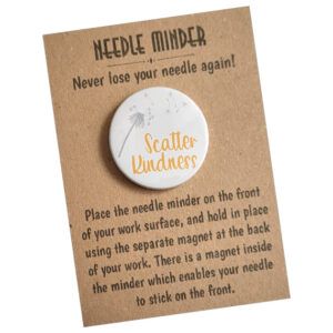Scatter Kindness Needle Minder featuring a delicate grey dandelion design with the words ‘Scatter Kindness’ in cheerful orange script, round 38mm magnetic accessory for holding needles, patterns, or small scissors, displayed on kraft card packaging.