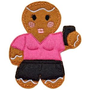 A handmade felt gingerbread girl decoration puckering her lips for a selfie, holding a mobile phone. She has embroidered facial details, a colourful outfit, and is available as a magnet, hanging ornament, keyring, or keepsake.
