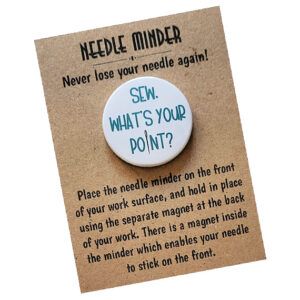 Round needle minder with white background and teal text reading ‘Sew, What’s Your Point?’ with a needle graphic replacing the letter i. Displayed on kraft card packaging that says ‘Needle Minder – Never lose your needle again!’ along with usage instructions.
