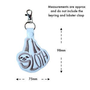 Embroidered sloth word art keyring on white faux leather with grey stitching, measuring approximately 75mm wide and 98mm high, excluding the keyring and lobster clasp.